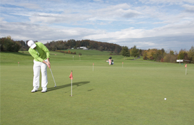 Distanzkontrolle auf dem Putting Green demonstriert vom Golflehrer