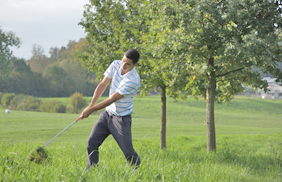 Golfer spielt seinen Ball aus dem hohen Gras