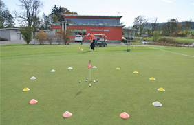 Golflehrer zeigt Distanzübungen auf der Kurzspielanlage